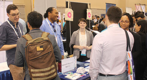 A diverse group of employers and jobseekers speaking at an INFORMS career fair