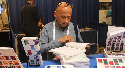 Annual Meeting attendee flipping through an INFORMS journal at an exhibit booth