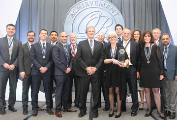 Jean Kiddoo(拿着奖)和FCC的Edelman奖团队的其他成员在赢得“超级碗的手术”后都是微笑的，前INFORMS总裁Michael Trick(从左第六)和Karla Hoffman(从右第三)是团队的关键成员。